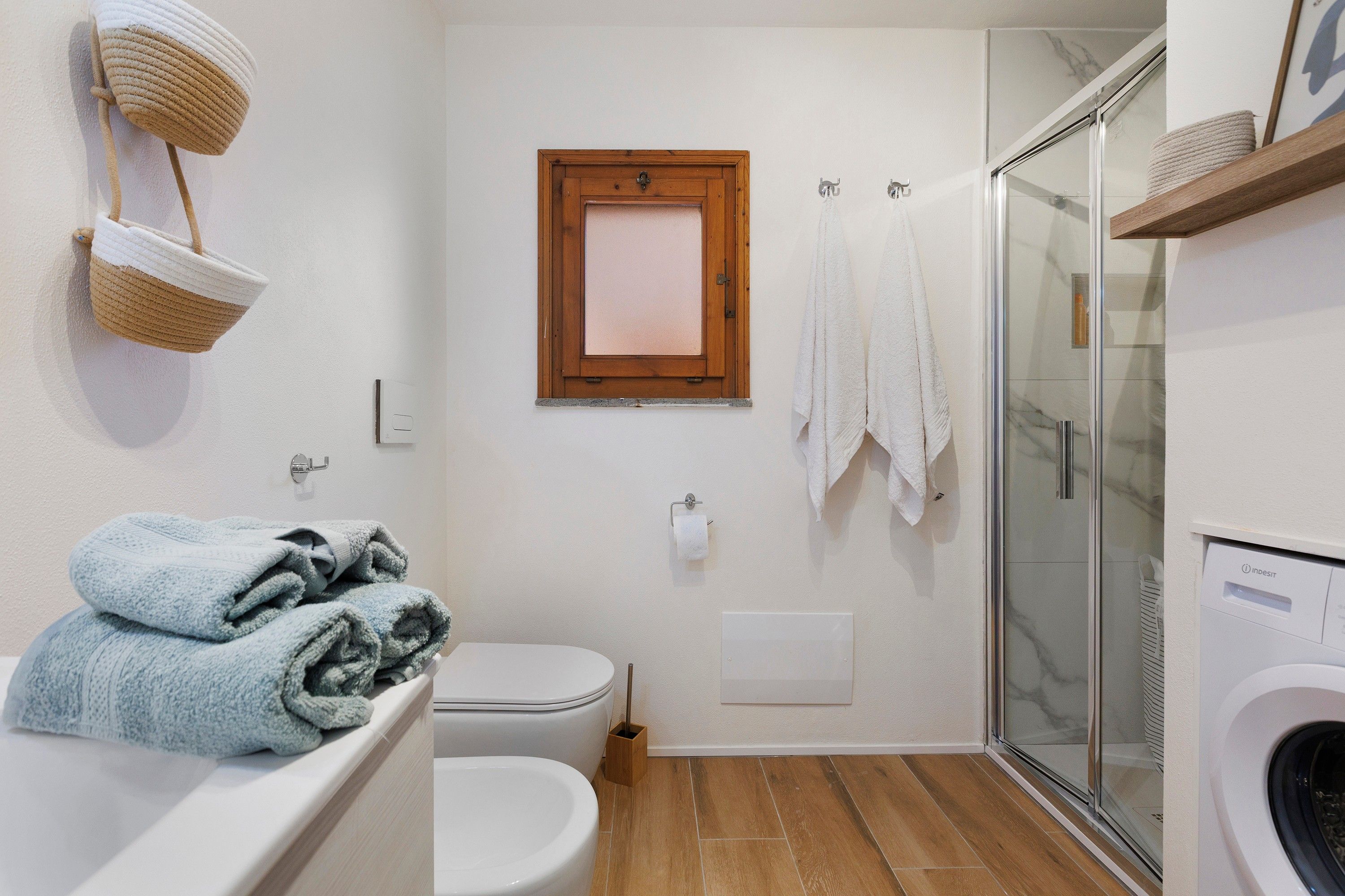A bathroom with a toilet, a shower, and a washing machine.