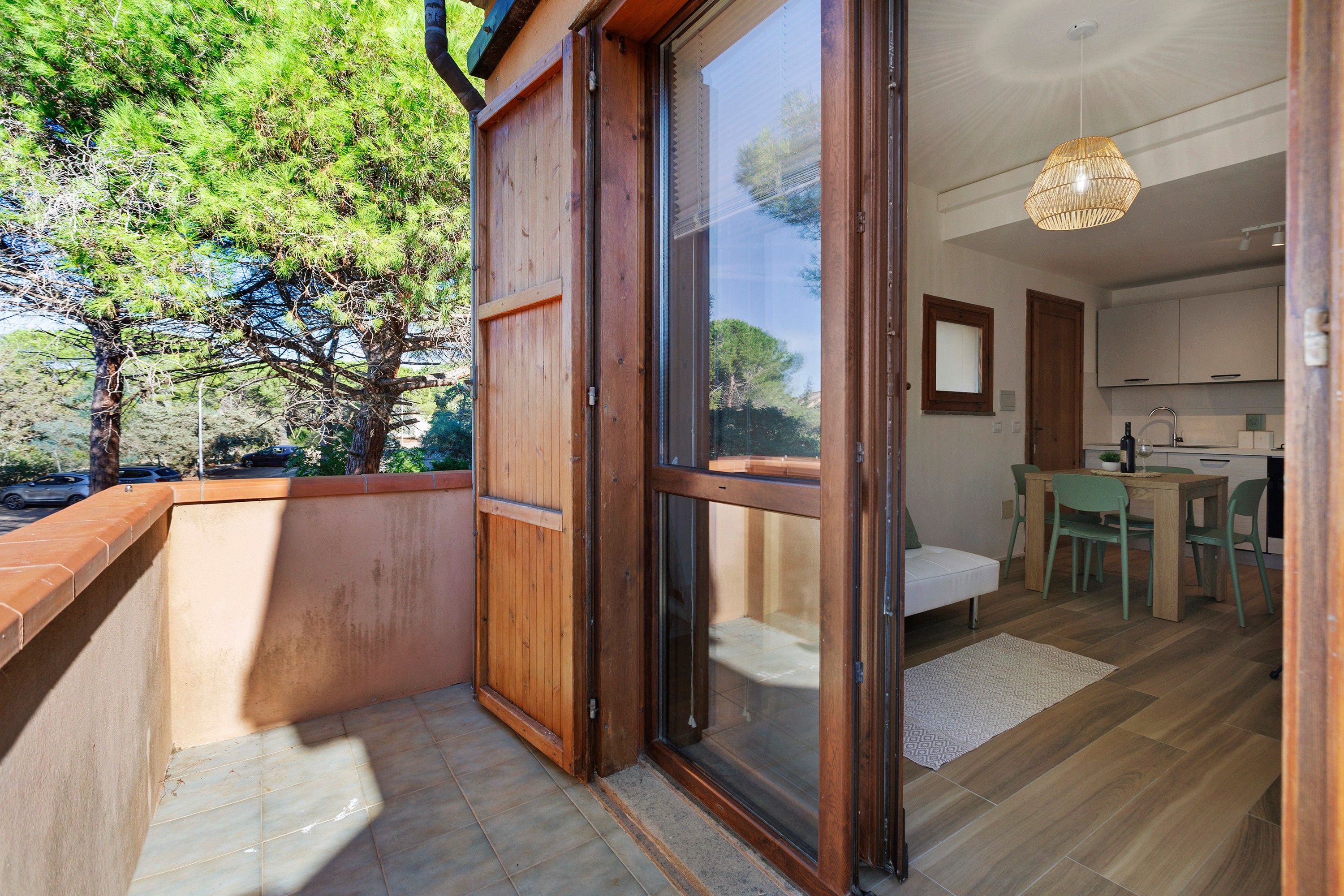 A modern kitchen with a dining area, a wooden exterior door, and a view of a tree.