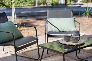 Two outdoor chairs with cushions, a table with a woven placemat, and two patterned mugs. - Apartment 'Salsedine's House' with Private Garden, Wi-Fi and Air Conditioning (Arboriamar)