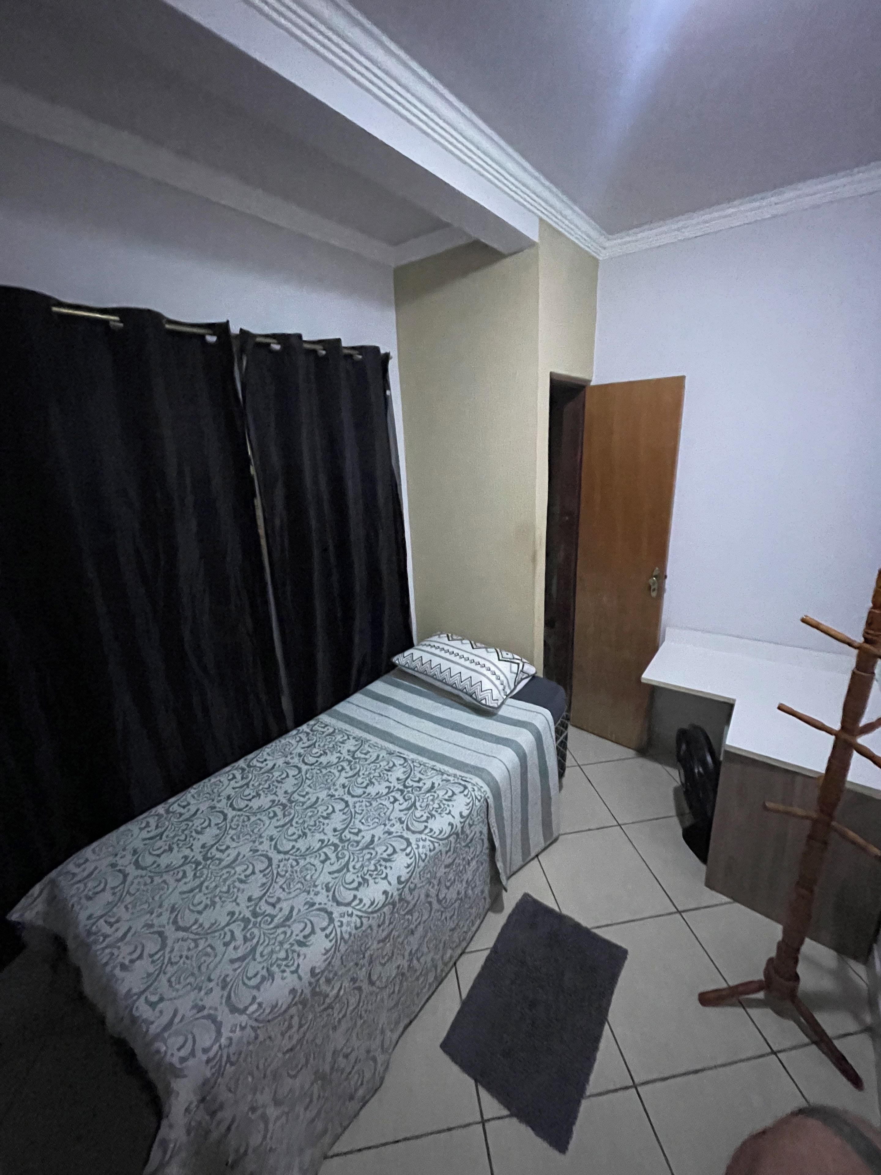 Une chambre à coucher avec un lit, un bureau, une chaise, une armoire et une porte.