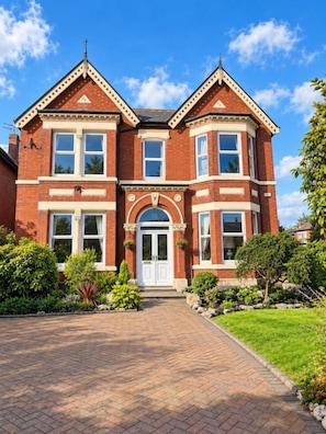 A two-story brick house with a central entrance, a driveway, and well-maintained landscaping. - Hartwood Falls (Southport)
