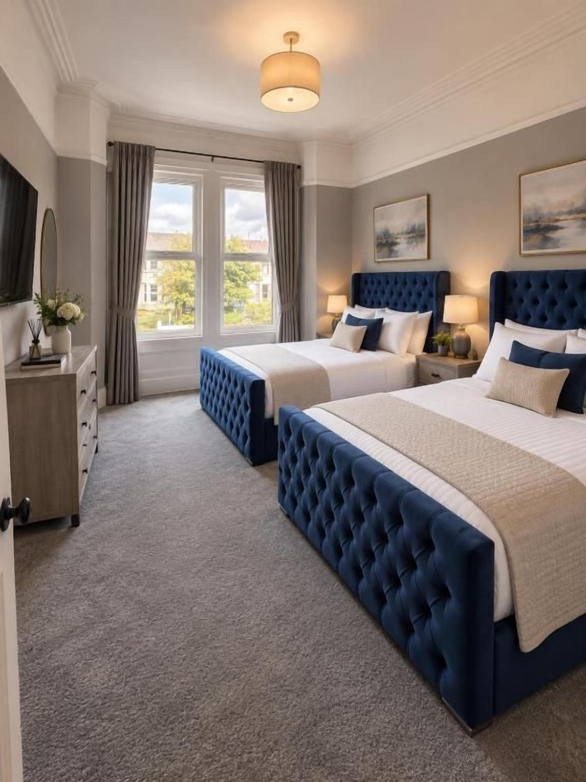 A hotel room with two beds, a large window, and a view of the outside.