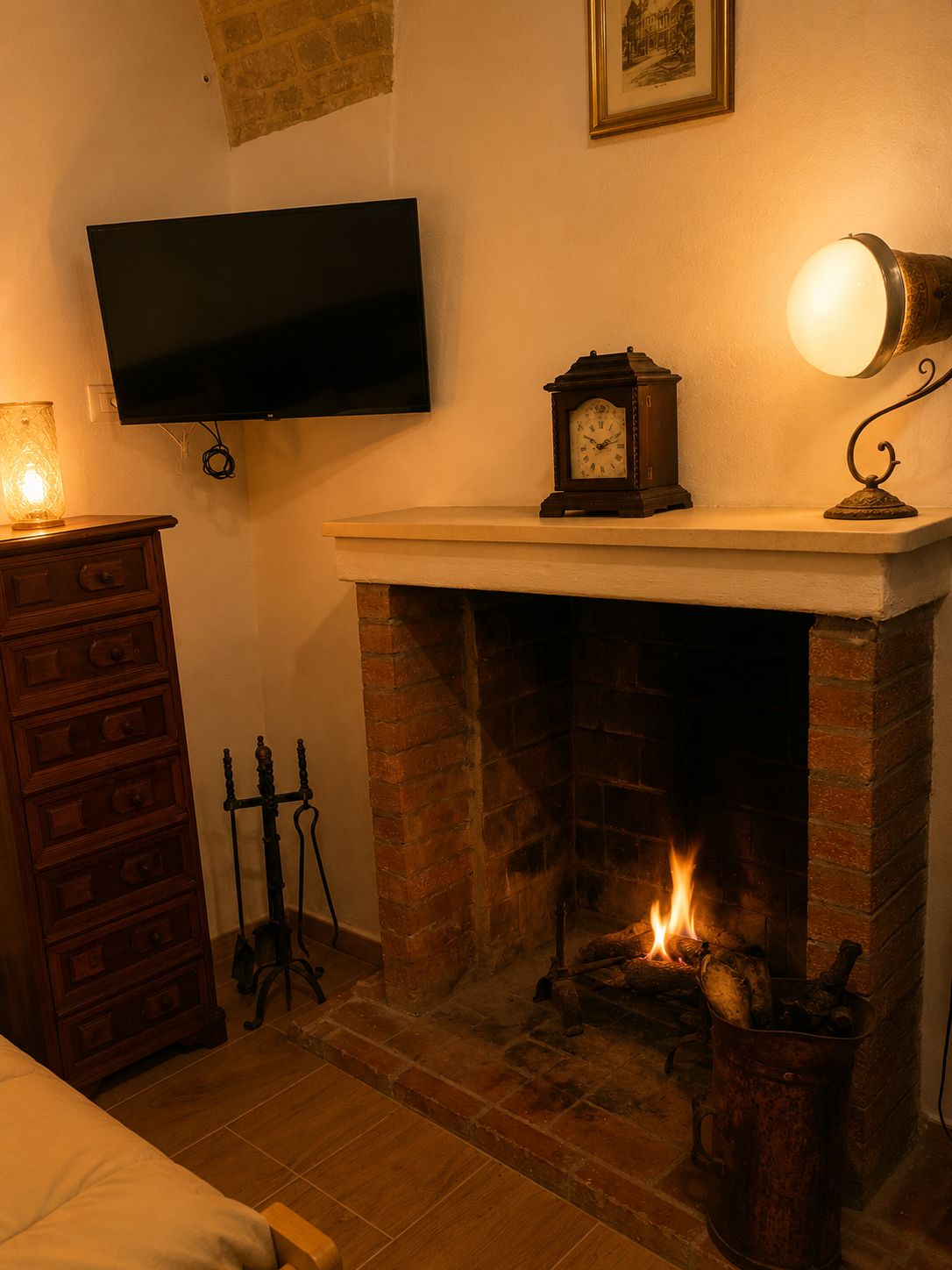 Een kamer met een open haard, een aan de muur bevestigde televisie, een houten dressoir en een lamp.
