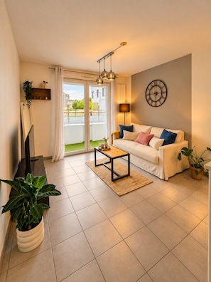 A living room with a sofa, coffee table, TV, and plants. - Le Cocon de Saint-Herblain, private parking (Saint-Herblain)
