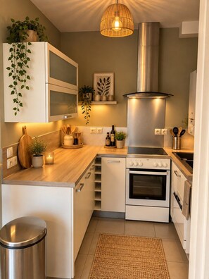 A modern kitchen with white cabinetry, a stainless steel range hood, and a wooden countertop. - Le Cocon de Saint-Herblain, private parking (Saint-Herblain)