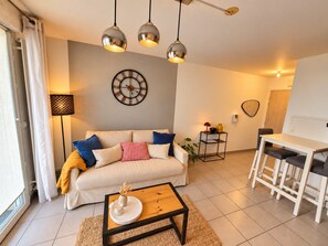 Un salon avec un canapé, une table basse et des lampes suspendues.