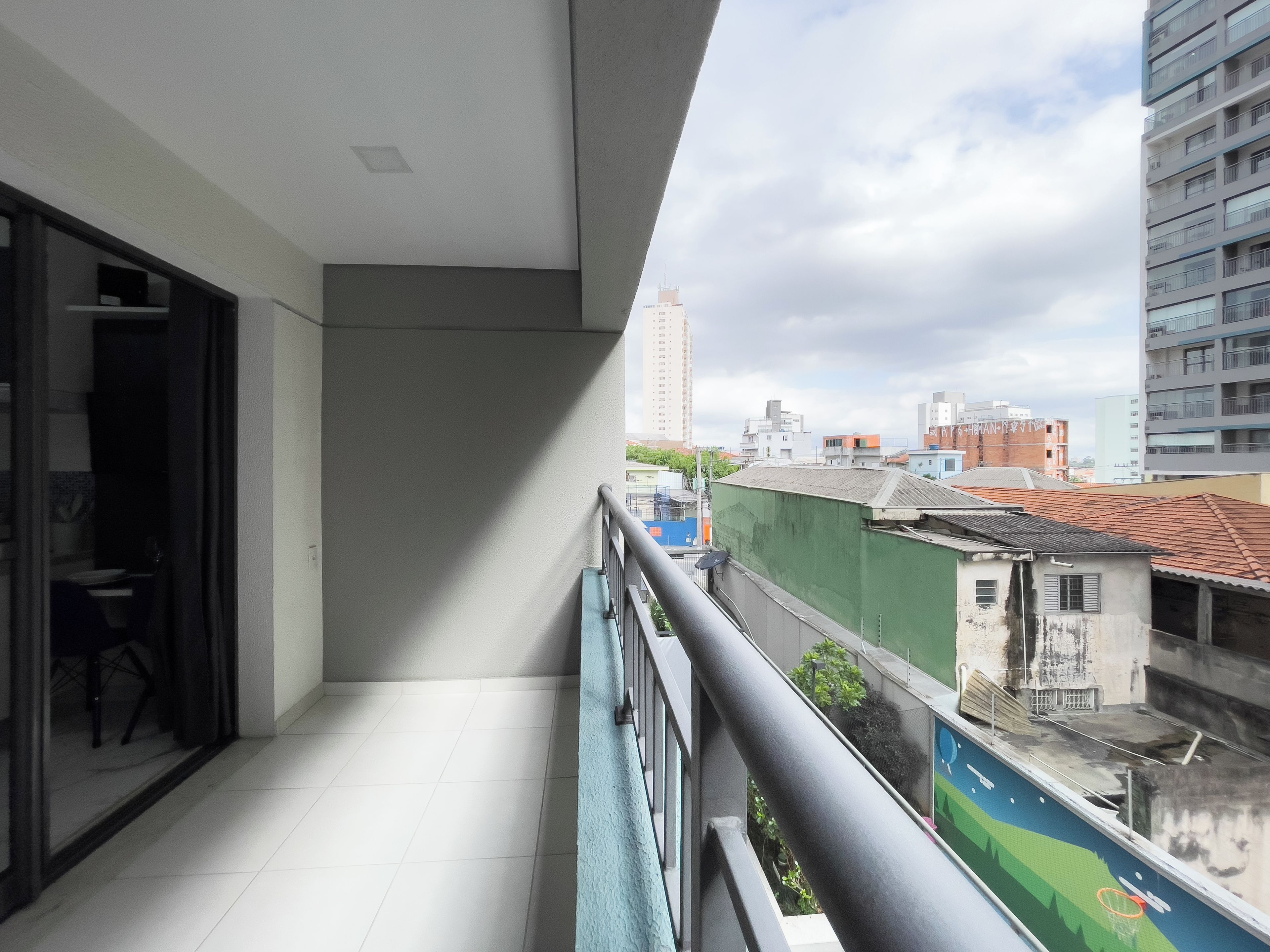 Un balcon offrant une vue sur le paysage urbain, avec des bâtiments et un ciel dégagé.