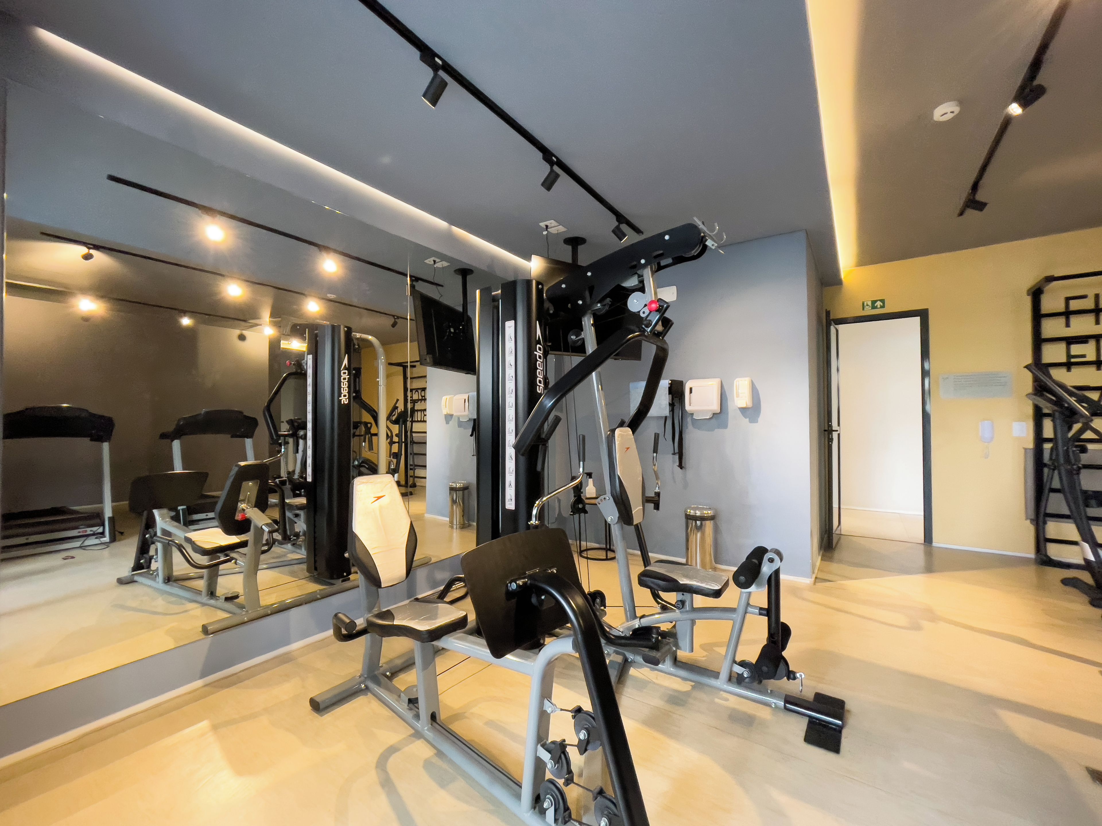 A gym with exercise equipment, a mirror, and a staircase.