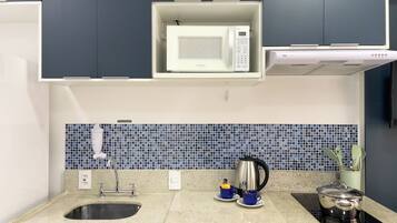 A modern kitchen with a built-in microwave, a kettle, and a stove.