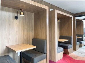 A modern interior with wooden panel walls, built-in seating with attached tables, and pendant lighting. - Raízes Tucuruvi Jacarandá (São Paulo)