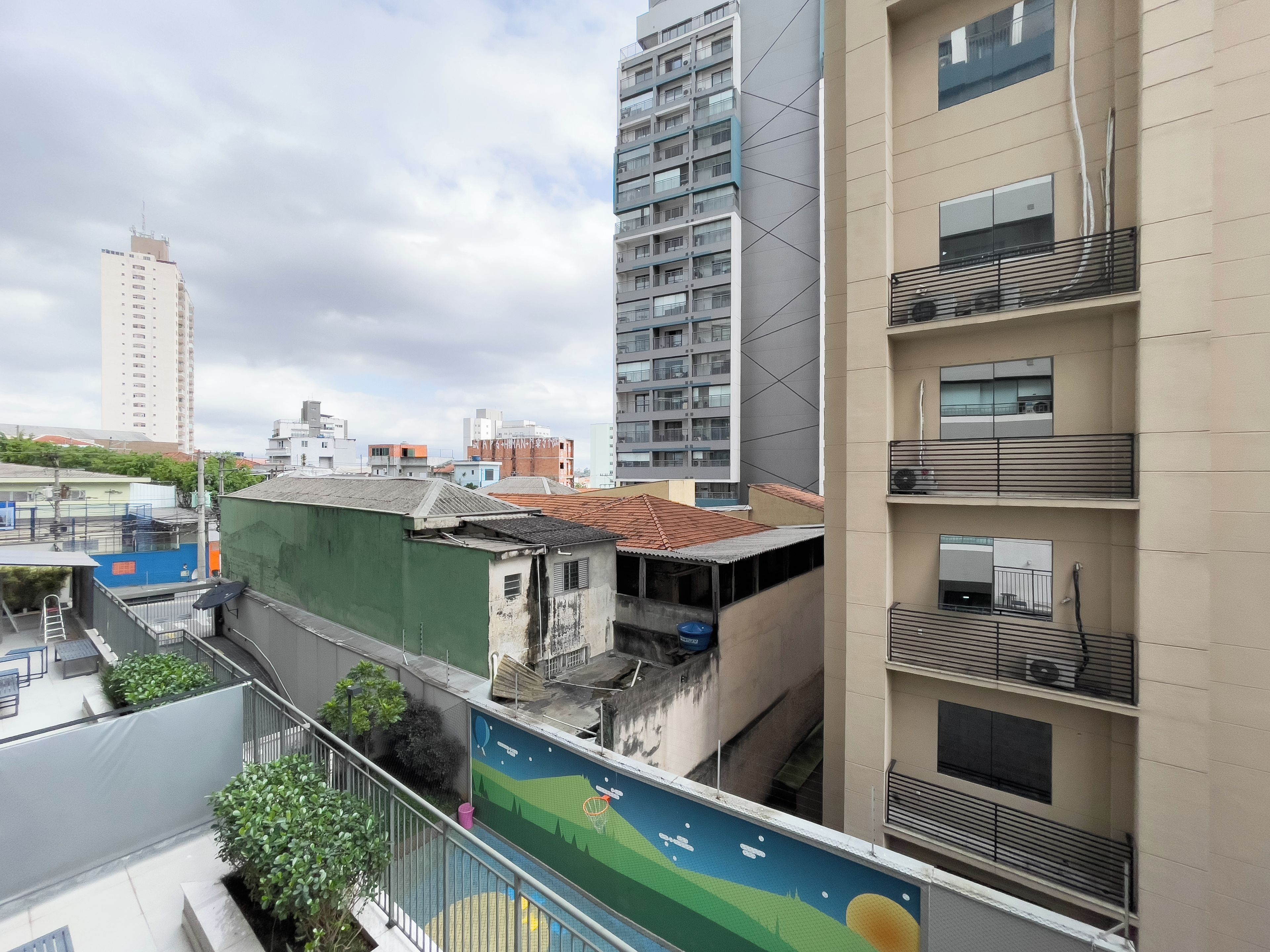 A multi-story building with balconies, a rooftop terrace, and a playground area.