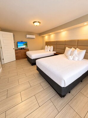 A hotel room with two beds, a television, and a wall-mounted air conditioner. - Ocean Daydream at 300 Tenth | 108 (Myrtle Beach)