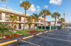 A hotel with a parking lot, palm trees, and a sign indicating 300 rooms. - Coastal Crush at 300 Tenth | 213 (Myrtle Beach)