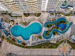 Ein Resort mit mehreren Schwimmbecken, einem großen zentralen Pool und verschiedenen Liegebereichen.