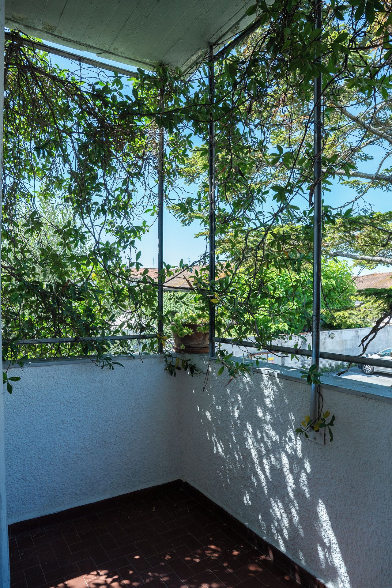 A balcony with a view of trees and a building in the background.