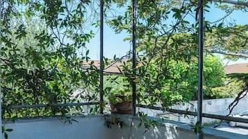 A balcony with a view of trees and a building in the background.