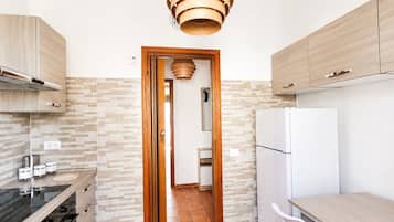 Una cucina moderna con isola centrale, mobili in legno, forno integrato e lampadario a sospensione.