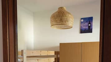 Une chambre avec un lit superposé, une armoire et un luminaire suspendu.
