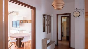 Un interno moderno con un tavolo da pranzo rotondo, sedie bianche, una lampada a sospensione in legno e un orologio a parete.