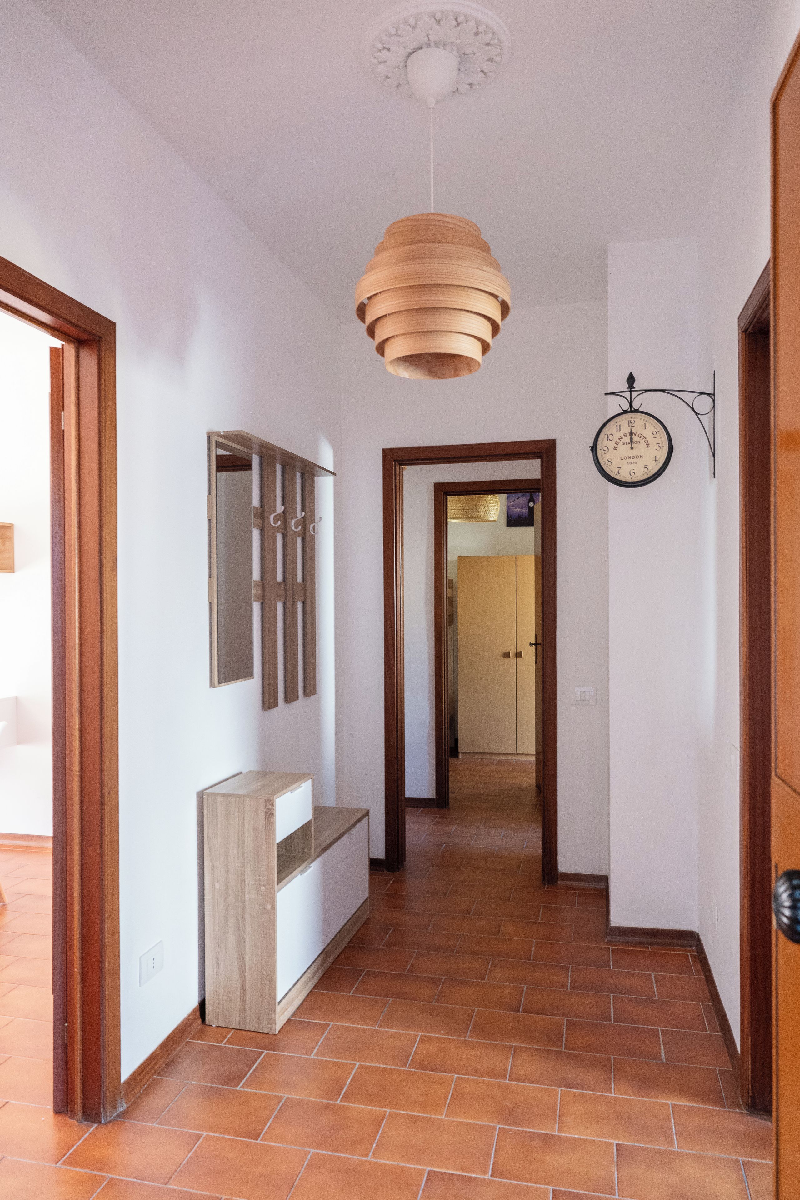 Ein Flur mit Deckenventilator aus Holz, einer Wanduhr und einem Spiegel.