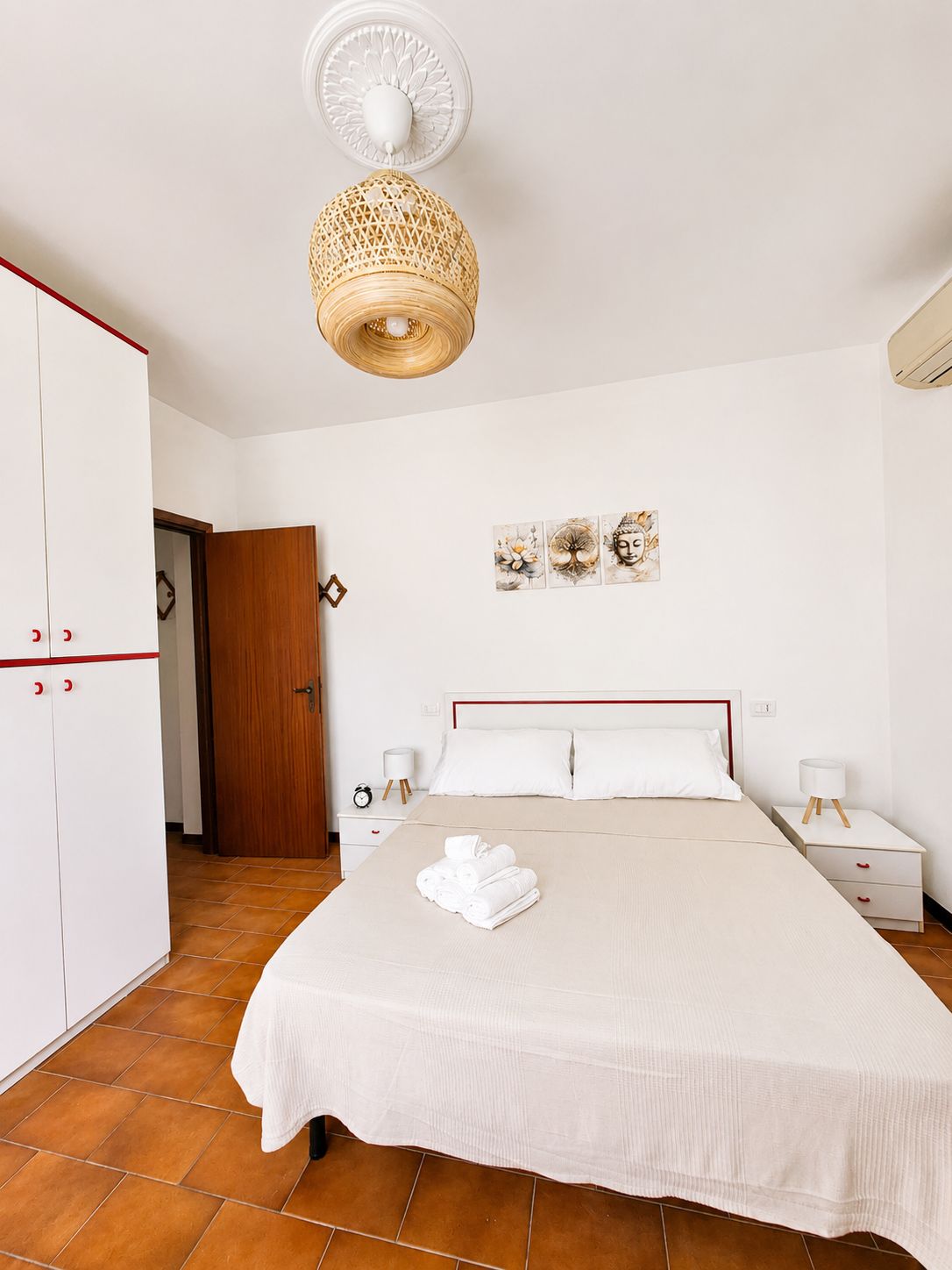 Una camera d'albergo con un letto, comodini, un armadio e un elemento decorativo a parete.