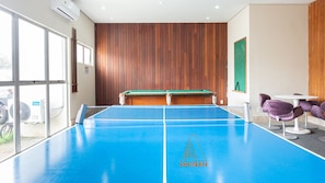 A billiards table with a blue playing surface, wooden panel walls, and purple chairs. - Conforto e Excelente Infraestrutura (Recife)