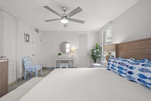 A bedroom with a bed, a desk, a chair, a ceiling fan, a window, and a door. - Walk to Beach | Free Parking | Condado 3BR (Condado)