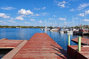 Un port de plaisance avec des bateaux amarrés, une jetée en bois et un ciel bleu dégagé.