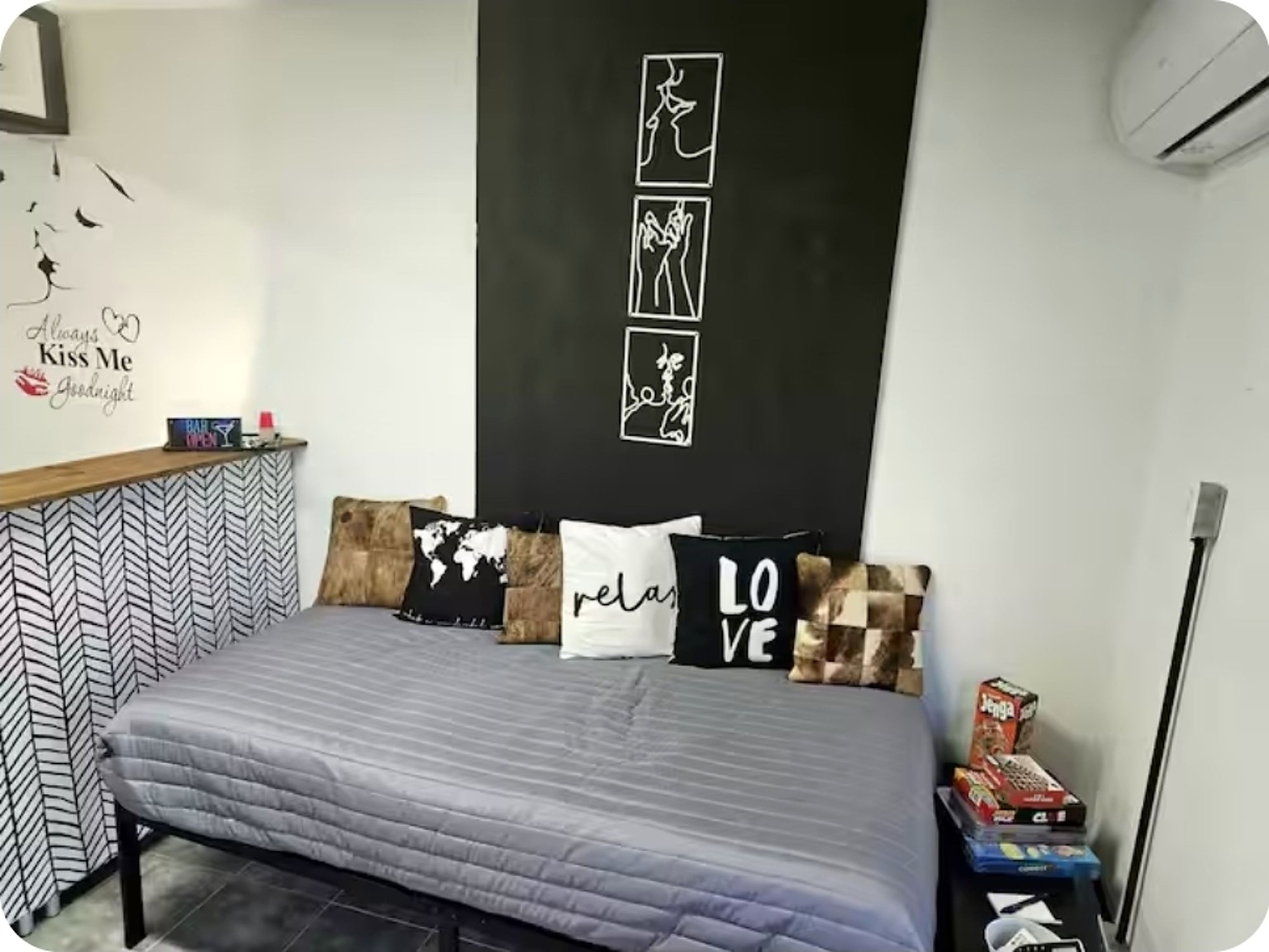 A bedroom with a bed, pillows, a world map pillow, a wall with a blackboard, and a shelf with items.