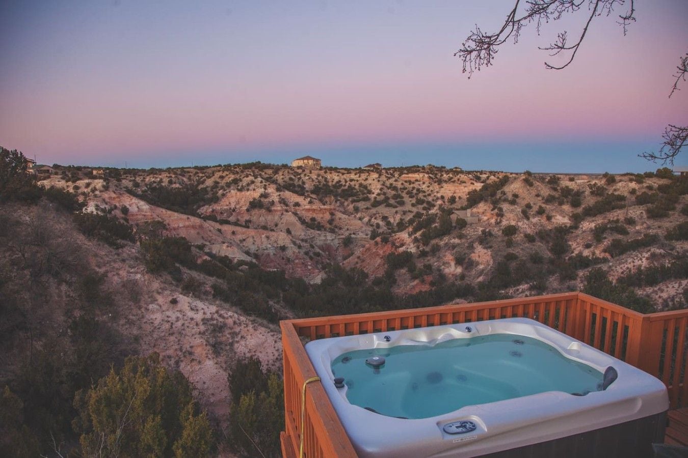 A hot tub on a wooden deck overlooking a hilly landscape.
