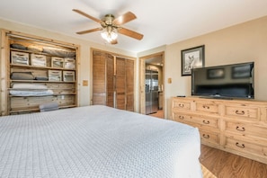 A bedroom with a bed, wooden wardrobe, a television, and a ceiling fan. - Clean Cozy Cabin, King beds, HotTub, Palo Duro (Canyon)