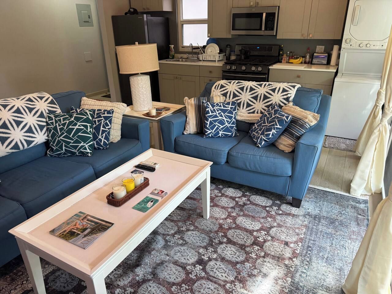 A living room with two sofas, a coffee table, and a kitchen in the background.