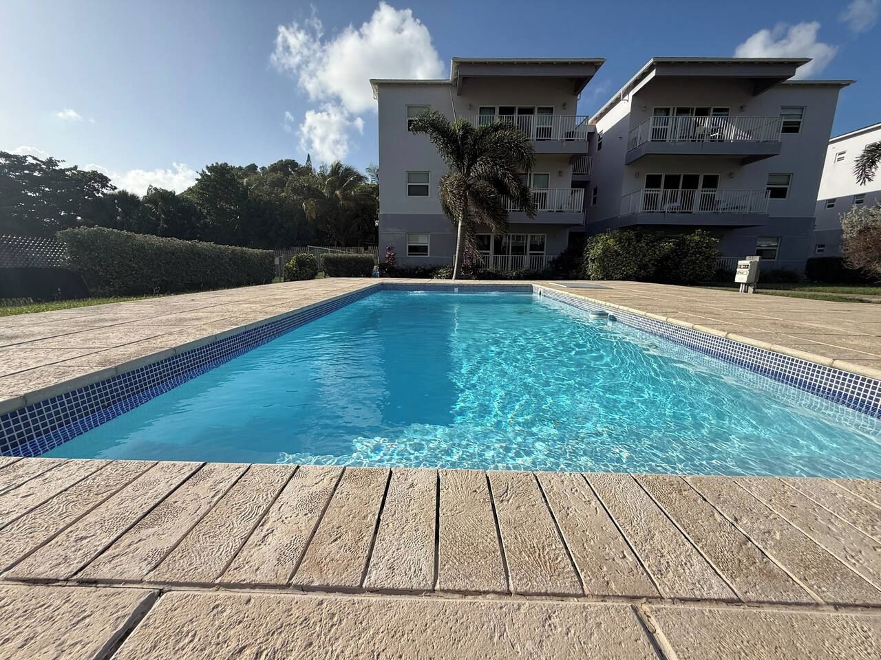 A rectangular swimming pool with clear blue water, surrounded by a wooden deck.