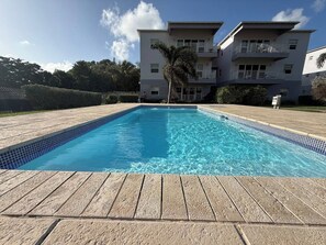 A rectangular swimming pool with clear blue water, surrounded by a wooden deck. - Luxurious Beach Front Villa Pool-Gym-AC Sleeps 5! (Turtle Bay)