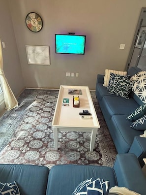 A living room with a sofa, a coffee table, a TV, and a patterned rug. - Luxurious Beach Front Villa Pool-Gym-AC Sleeps 5! (Turtle Bay)