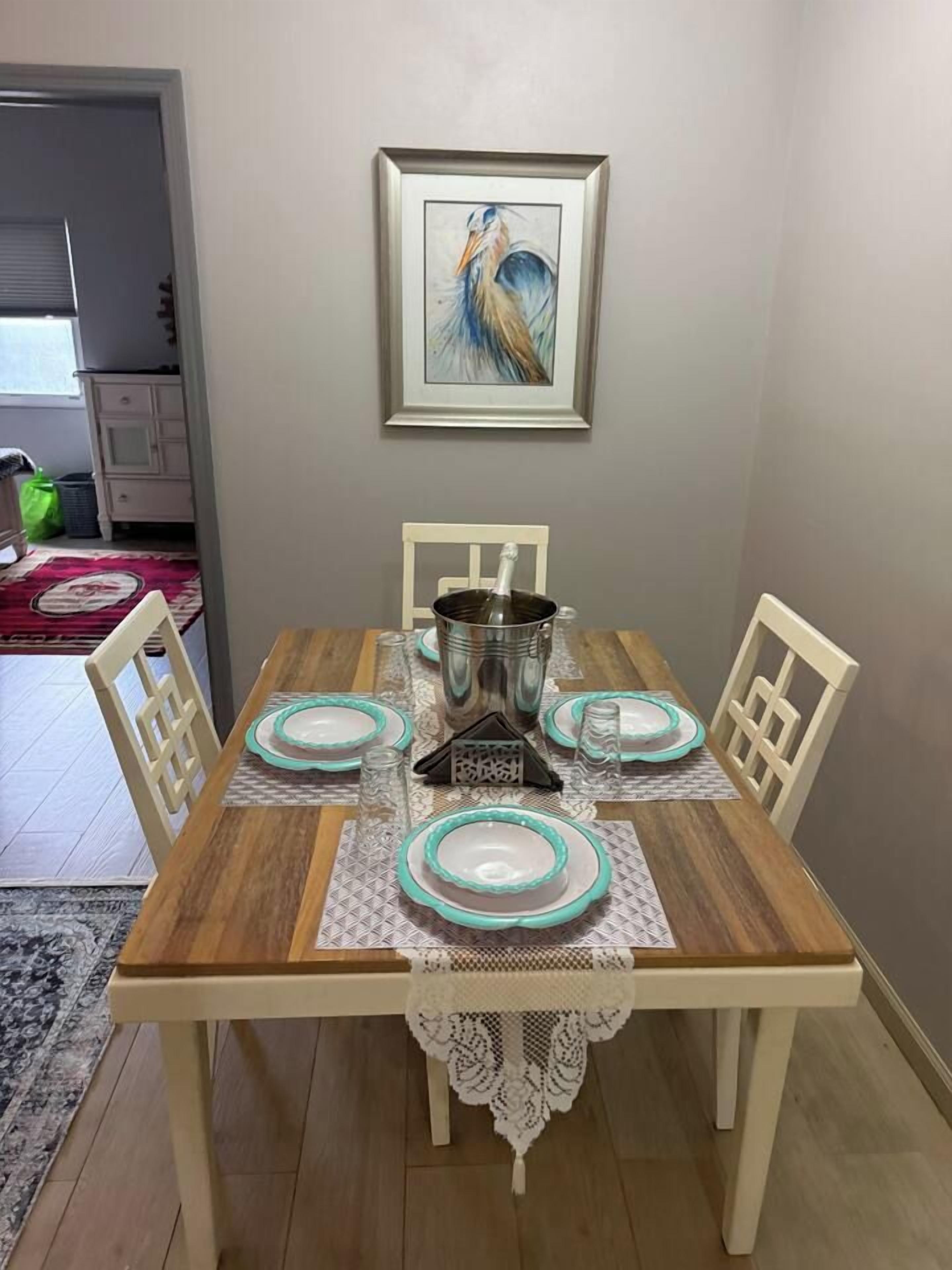 A dining table set with plates, a candle holder, and a framed artwork on the wall.