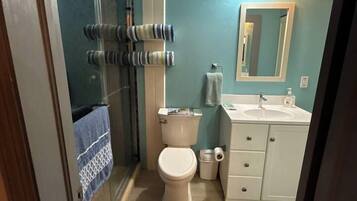 A bathroom with a toilet, sink, and shower area.