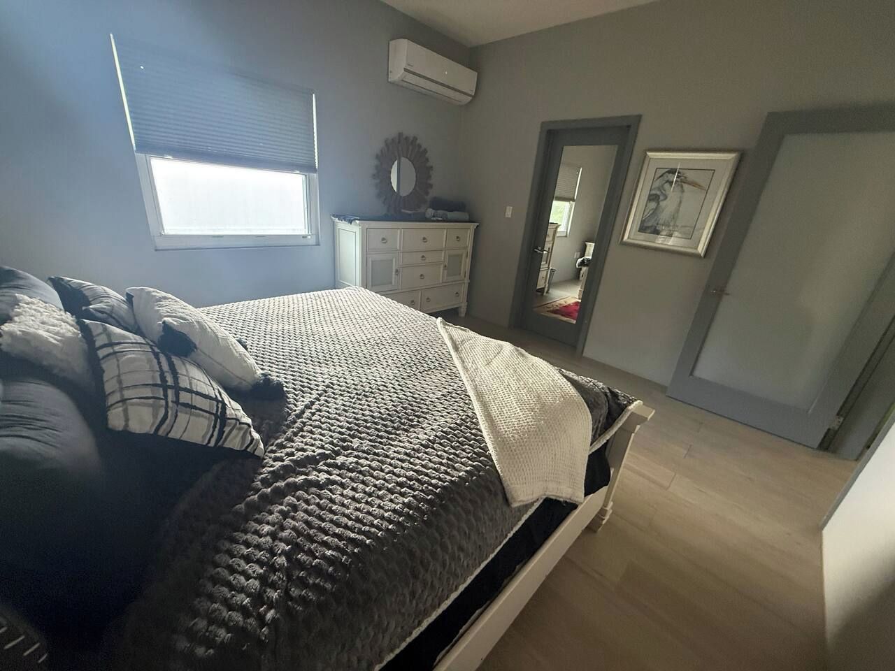 A bedroom with a bed, a dresser, a mirror, and a door.