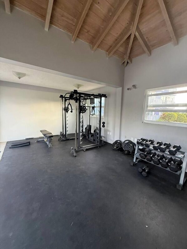 A gym with a ceiling beam structure, a squat rack, dumbbells, and a bench. - Luxurious Beach Front Villa Pool-Gym-AC Sleeps 5! (Turtle Bay)