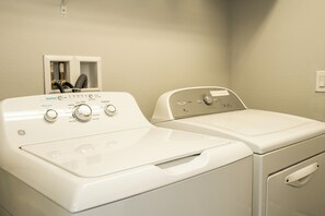 A laundry room with two front-loading washing machines and a dryer. - Cozy 5BR Pool Home Mario Game Room Near Disney (Kissimmee)