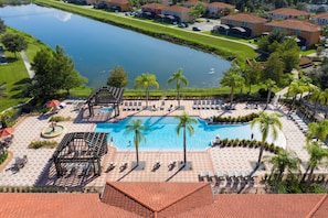 A resort with a swimming pool, lounge chairs, palm trees, and a view of a lake. - Near Disney Private Pool & Harry Potter Room (Kissimmee)