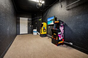 Een kamer met vloerbedekking, een witte deur en twee speelautomaten.