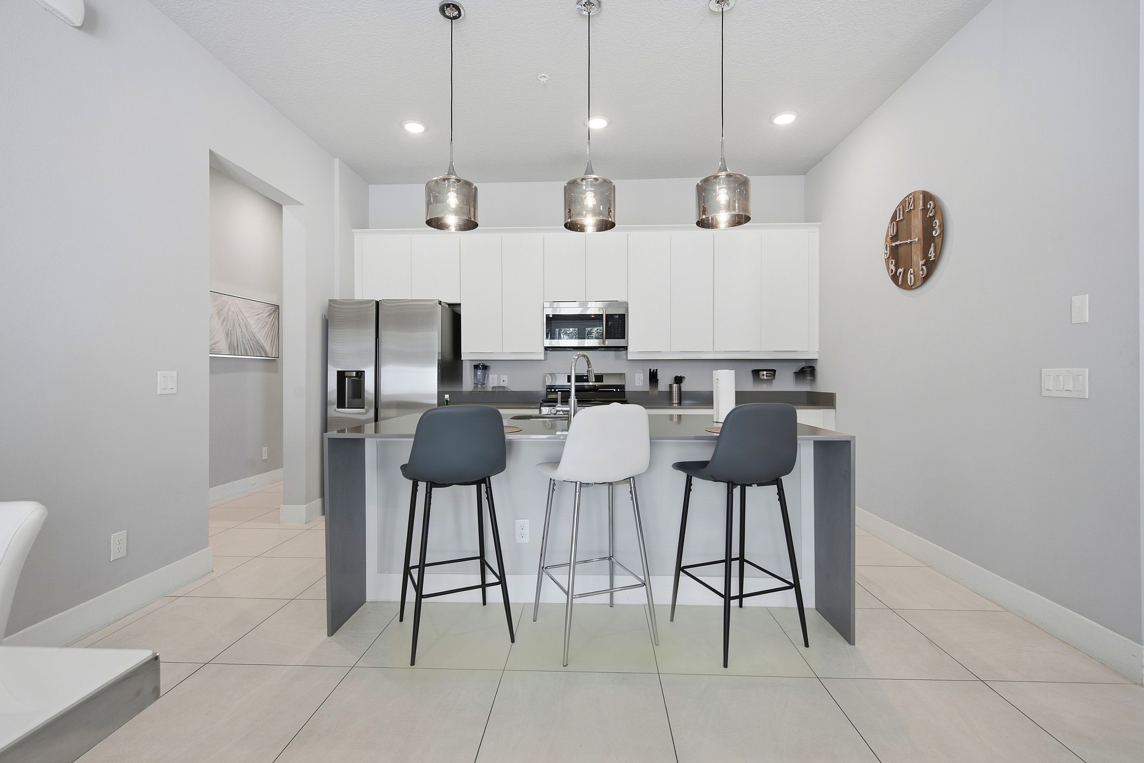 Una cocina moderna con una isla central, taburetes de bar e iluminación colgante.