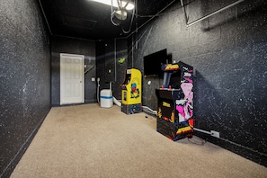 A room with a door, a white air purifier, a yellow and blue arcade machine, and a black and pink arcade machine. - Lakeside Trafalgar Pool Home, Themed Kids' Rooms (Kissimmee)