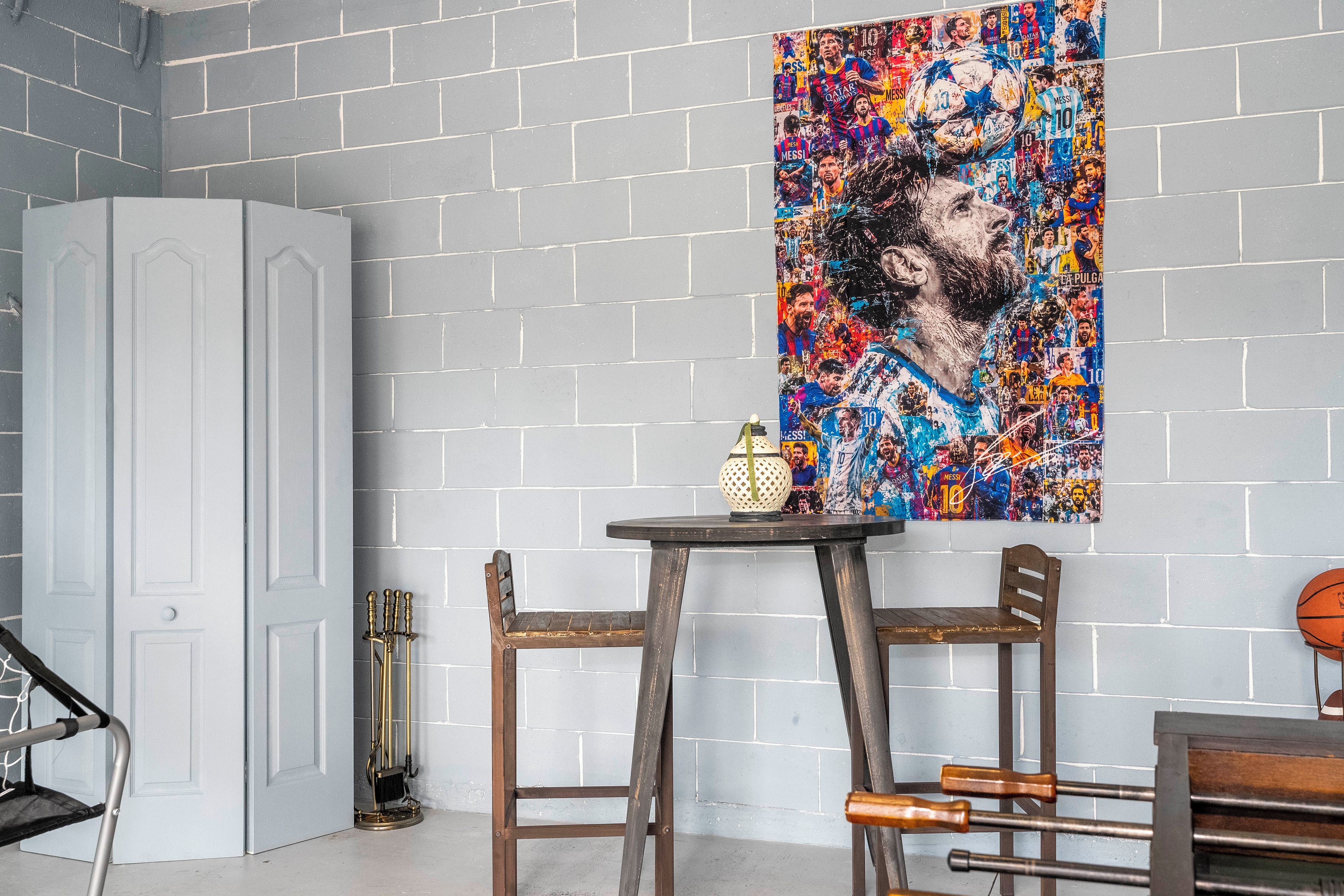 A room with a white brick wall, a door, a small table with a lamp, and a chair.