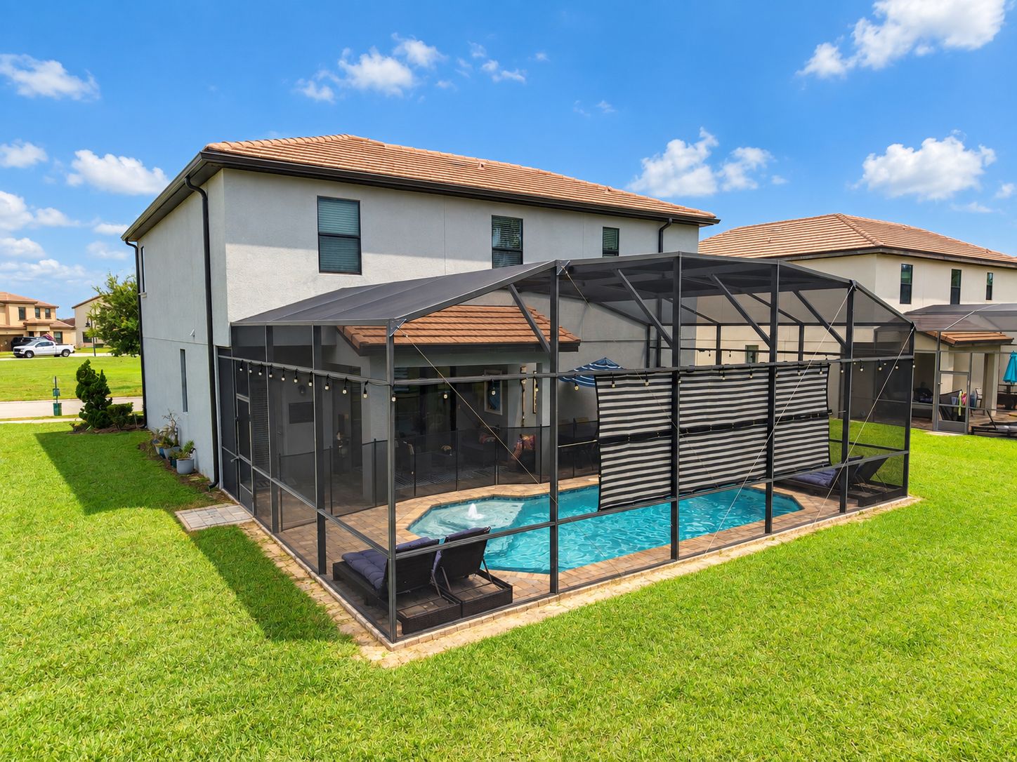 A residential property with a swimming pool, enclosed patio area, and a covered outdoor seating space.