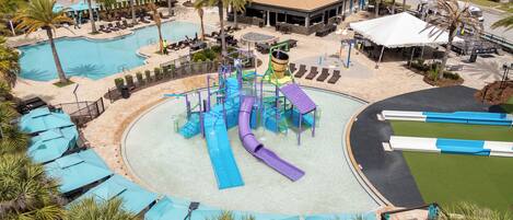 A water park with multiple slides and pools, surrounded by palm trees and lounge areas.