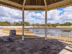 A covered pavilion with a view of a pond and trees.