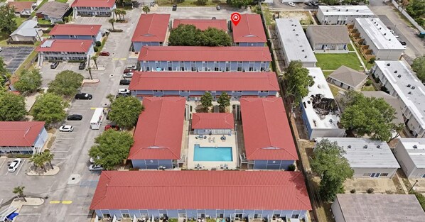 A multi-story hotel with a central swimming pool, surrounded by parking and greenery. - Gulf Getaway retreat by the sea. Quiet condo close to everywhere you want to be. (Biloxi)