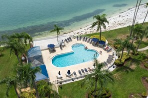 An aerial view of a resort with a heart-shaped pool, lounge chairs, and a beach. - Bayfront Condo Big Views Private Beach & Pool (St. Petersburg)